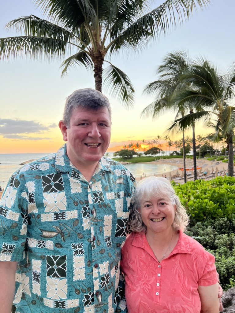 a man and woman standing together in front of palm trees