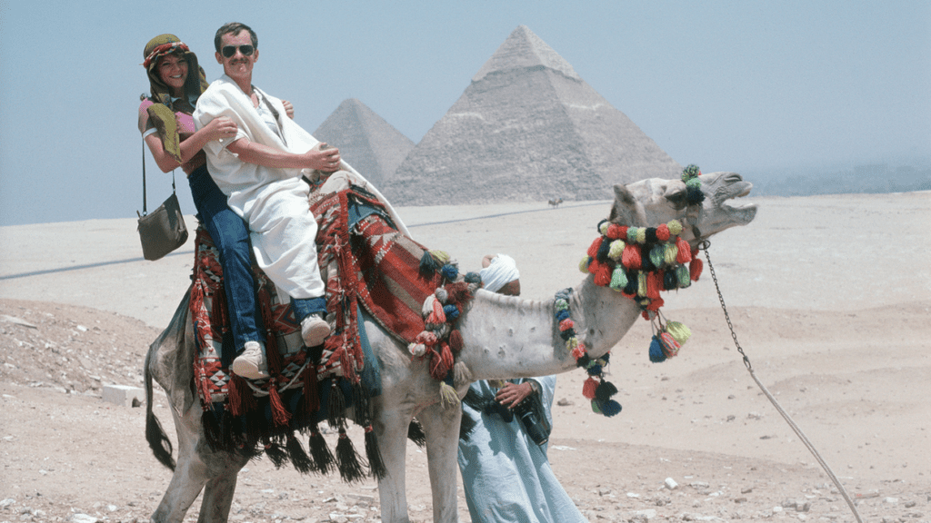 a man riding a camel with a group of people in the background