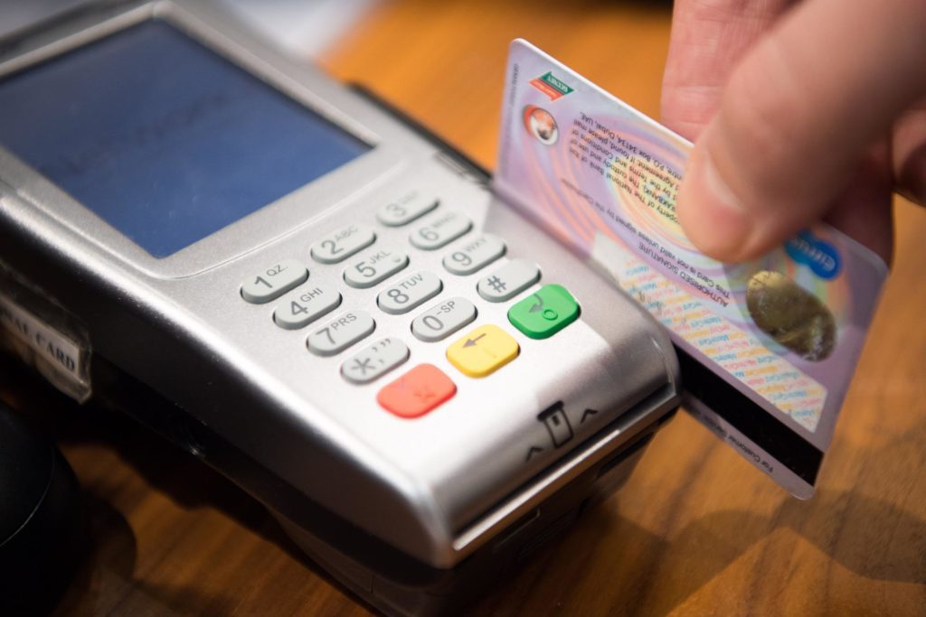 a person swiping a credit card through a credit card reader