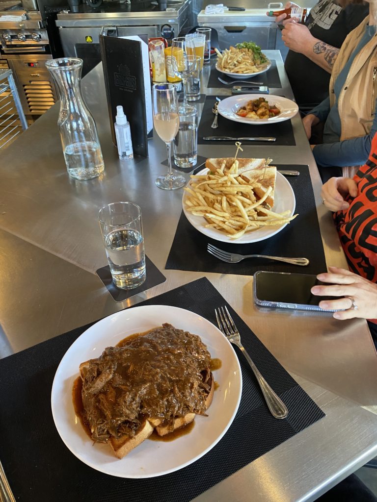 a table with plates of food and glasses of water and a phone