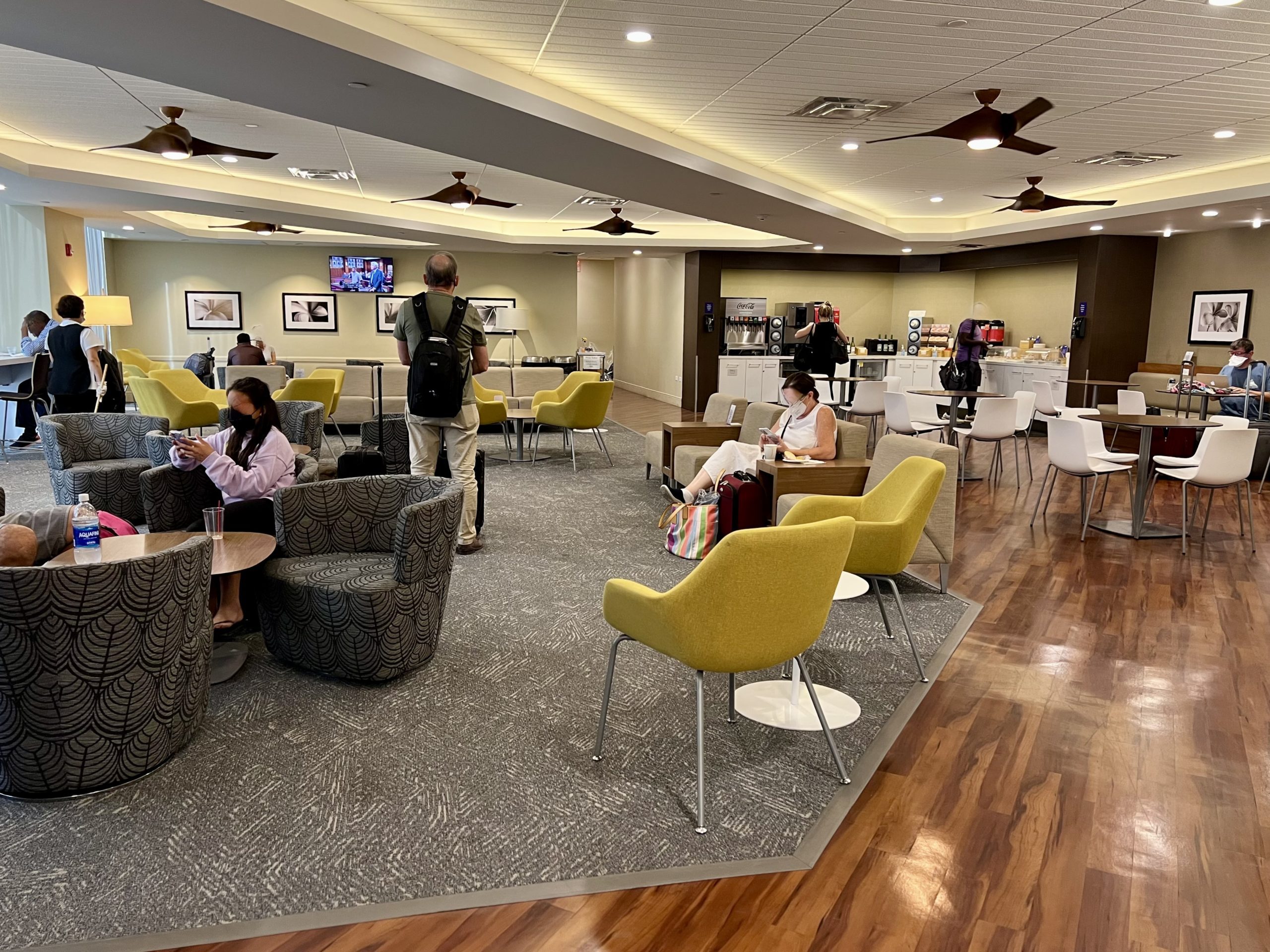 a group of people sitting at tables in a room with a ceiling fan