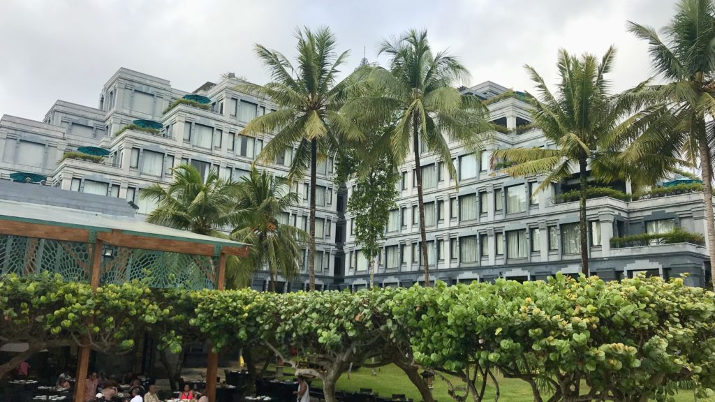 a building with palm trees and a group of people