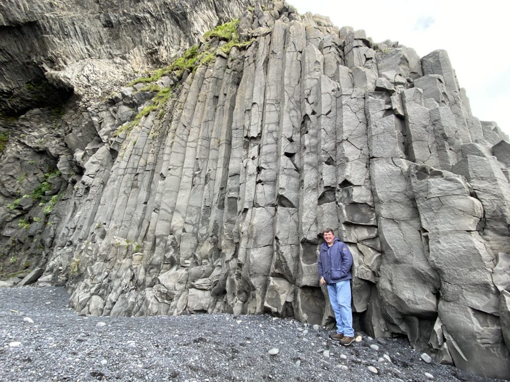 a man standing next to a rock wall