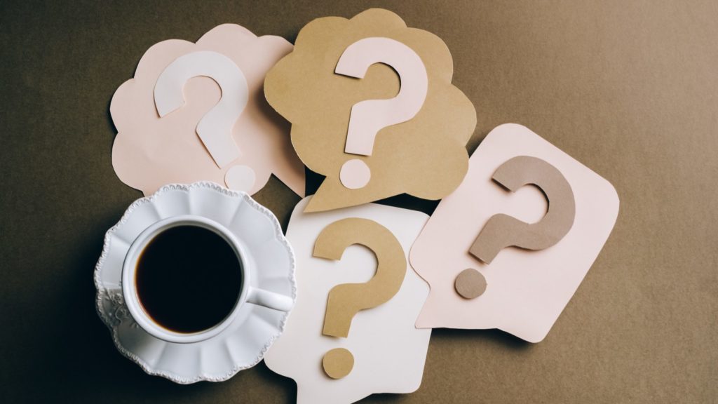 a cup of coffee and paper signs with question marks