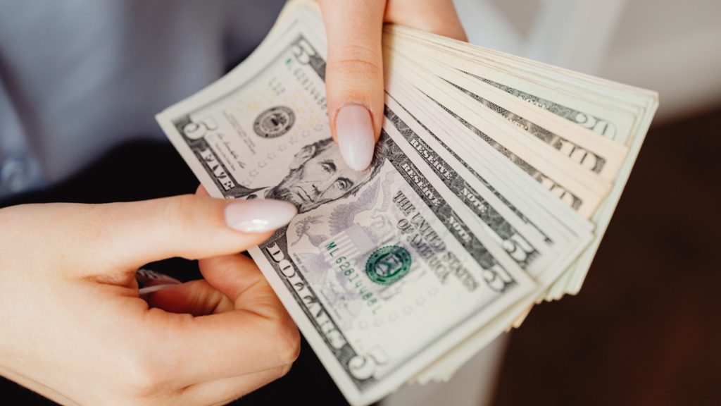 a hand holding a stack of paper money