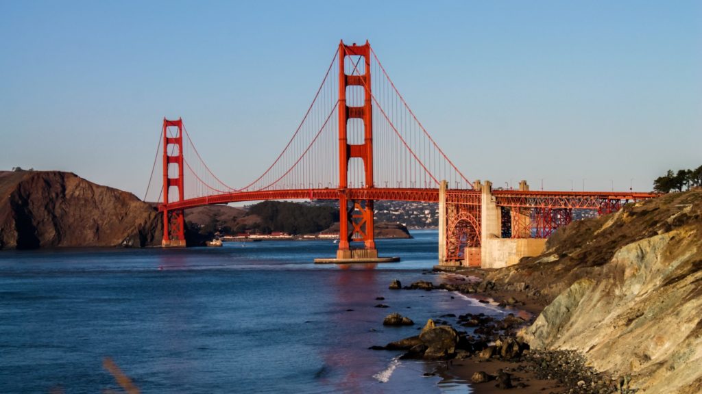 Golden Gate Bridge over water with rocks and a body of water