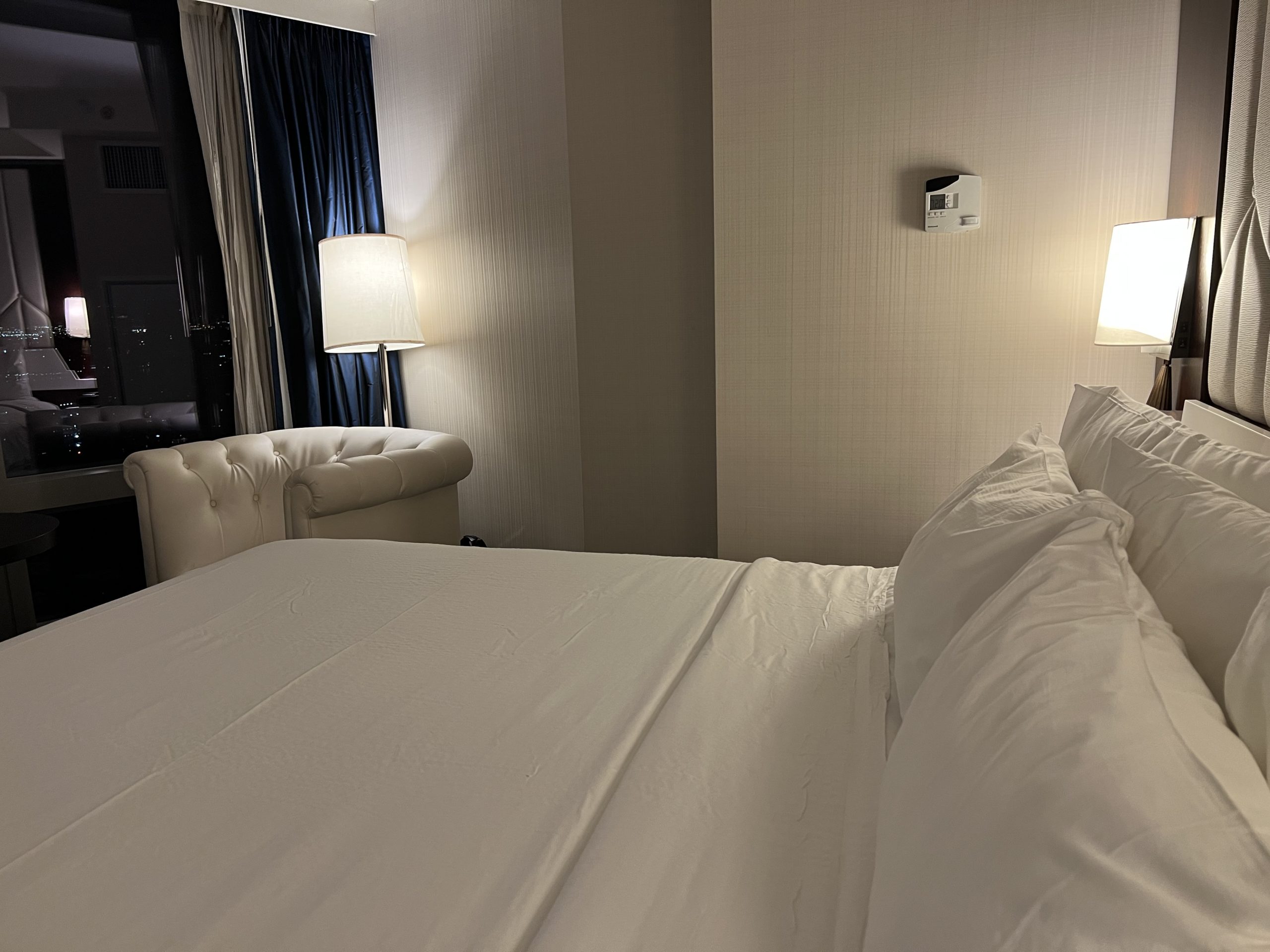 a bed with white sheets and a lamp