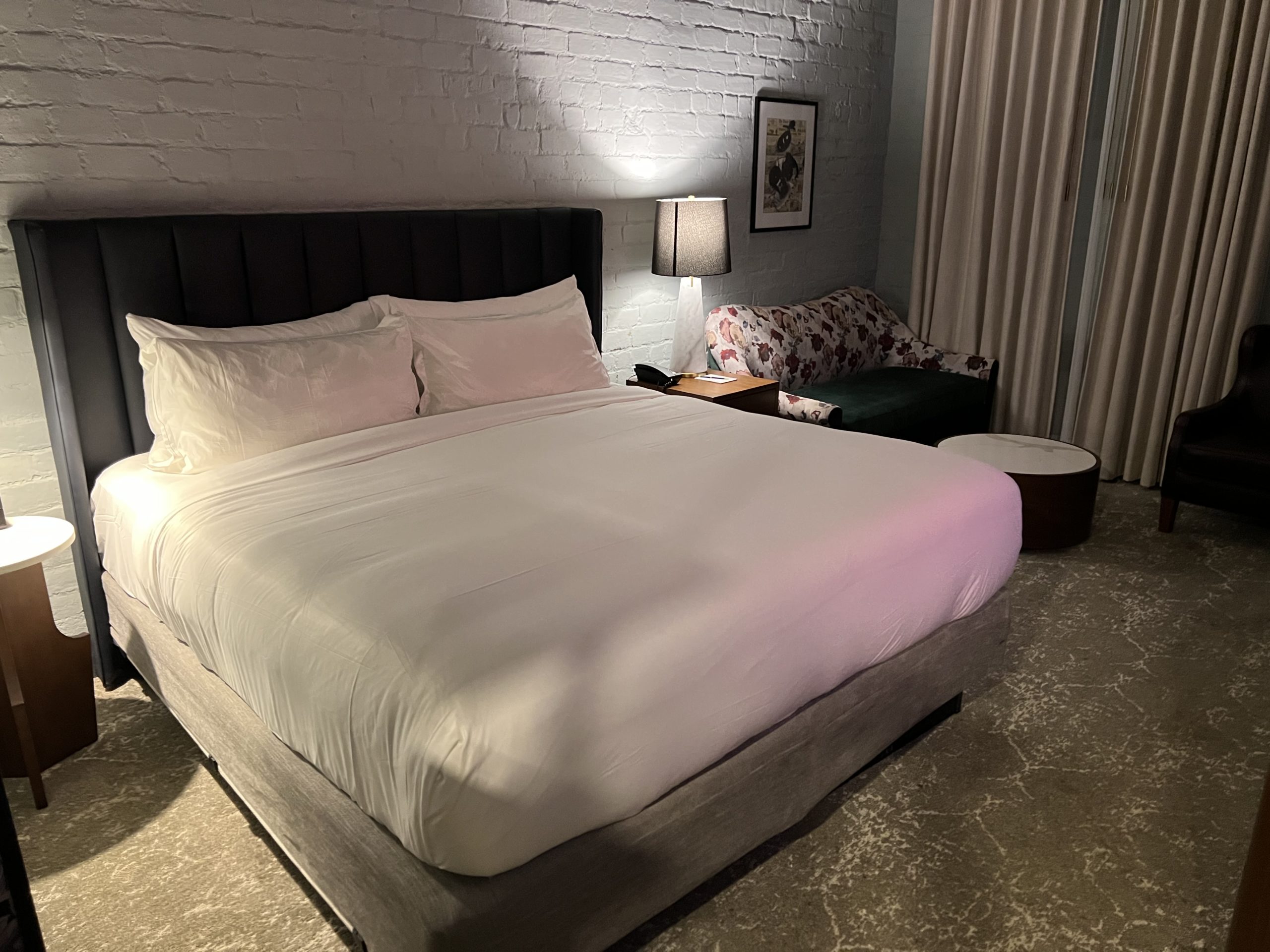 a bed with white sheets and a lamp in a room