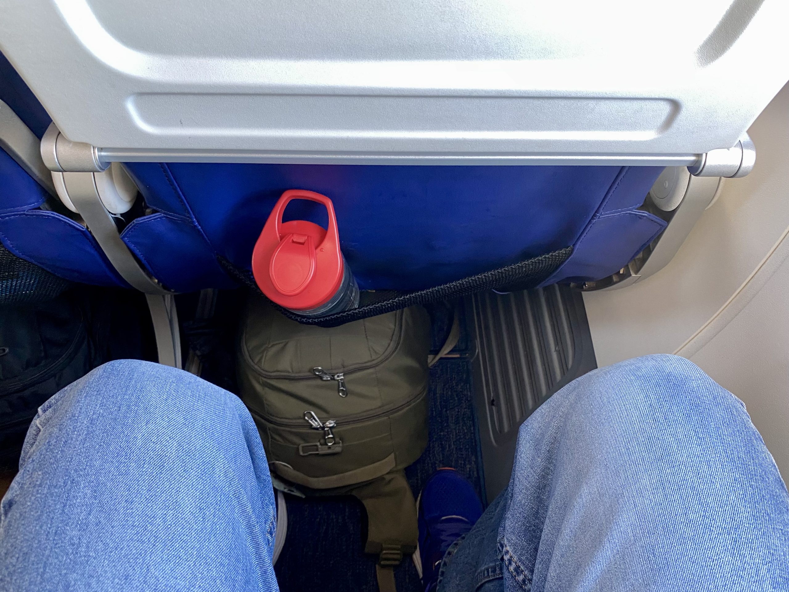 a person's legs and a backpack on a plane