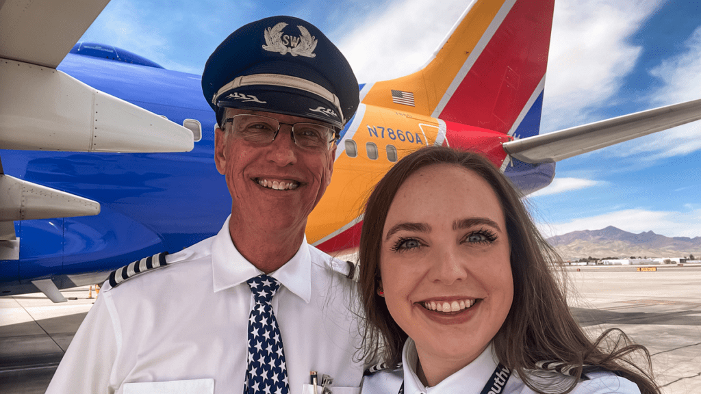 a man and woman in uniform standing in front of an airplane