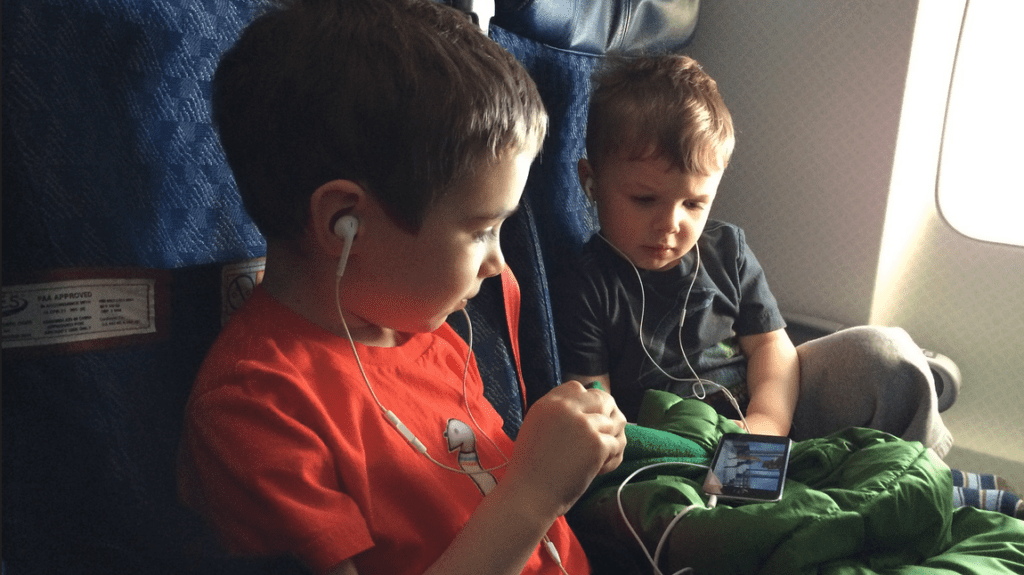 two boys sitting in a chair with headphones on