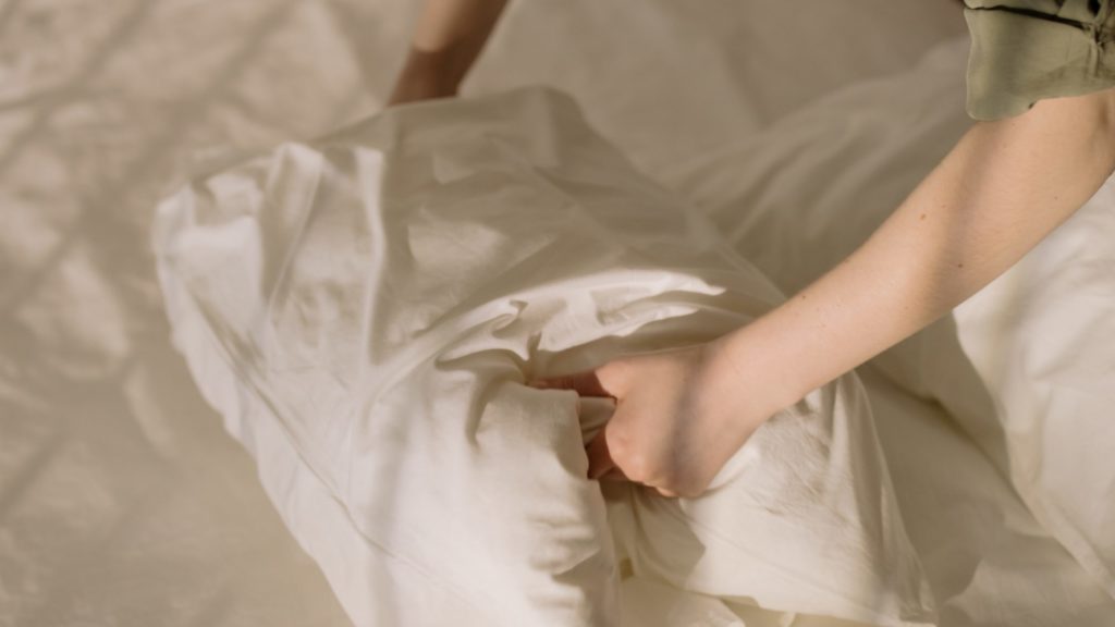 a person folding a white pillow