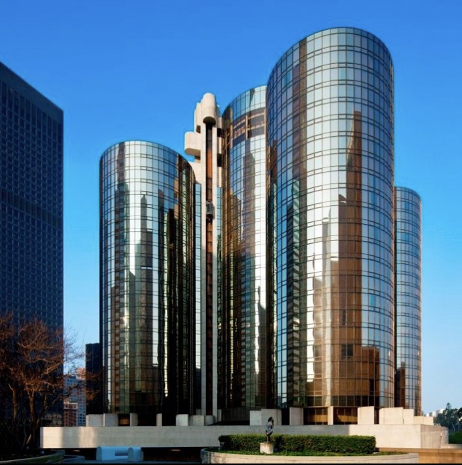 a tall glass building with a circular structure with Westin Bonaventure Hotel in the background