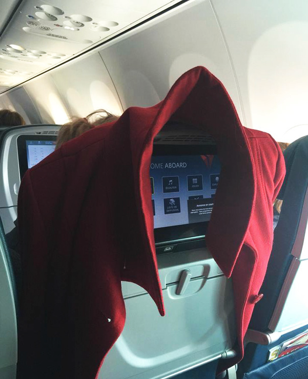 a red jacket over a screen on an airplane