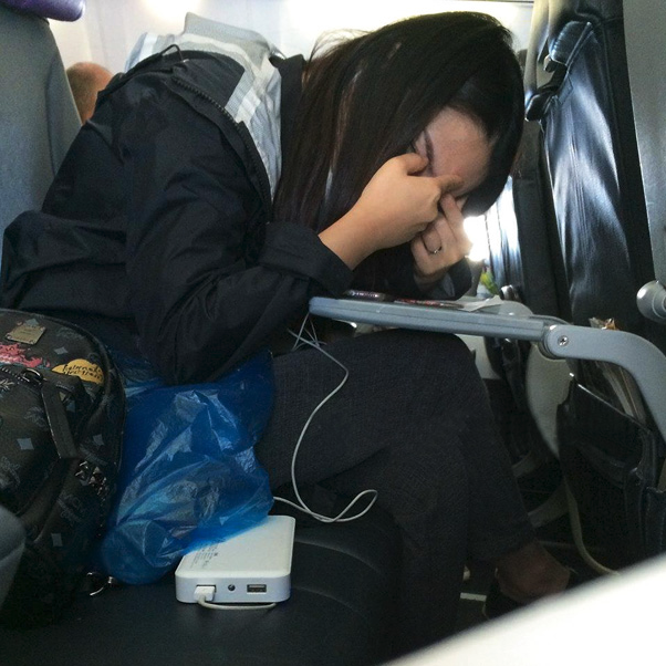 a woman sitting on a plane with her head in her hand