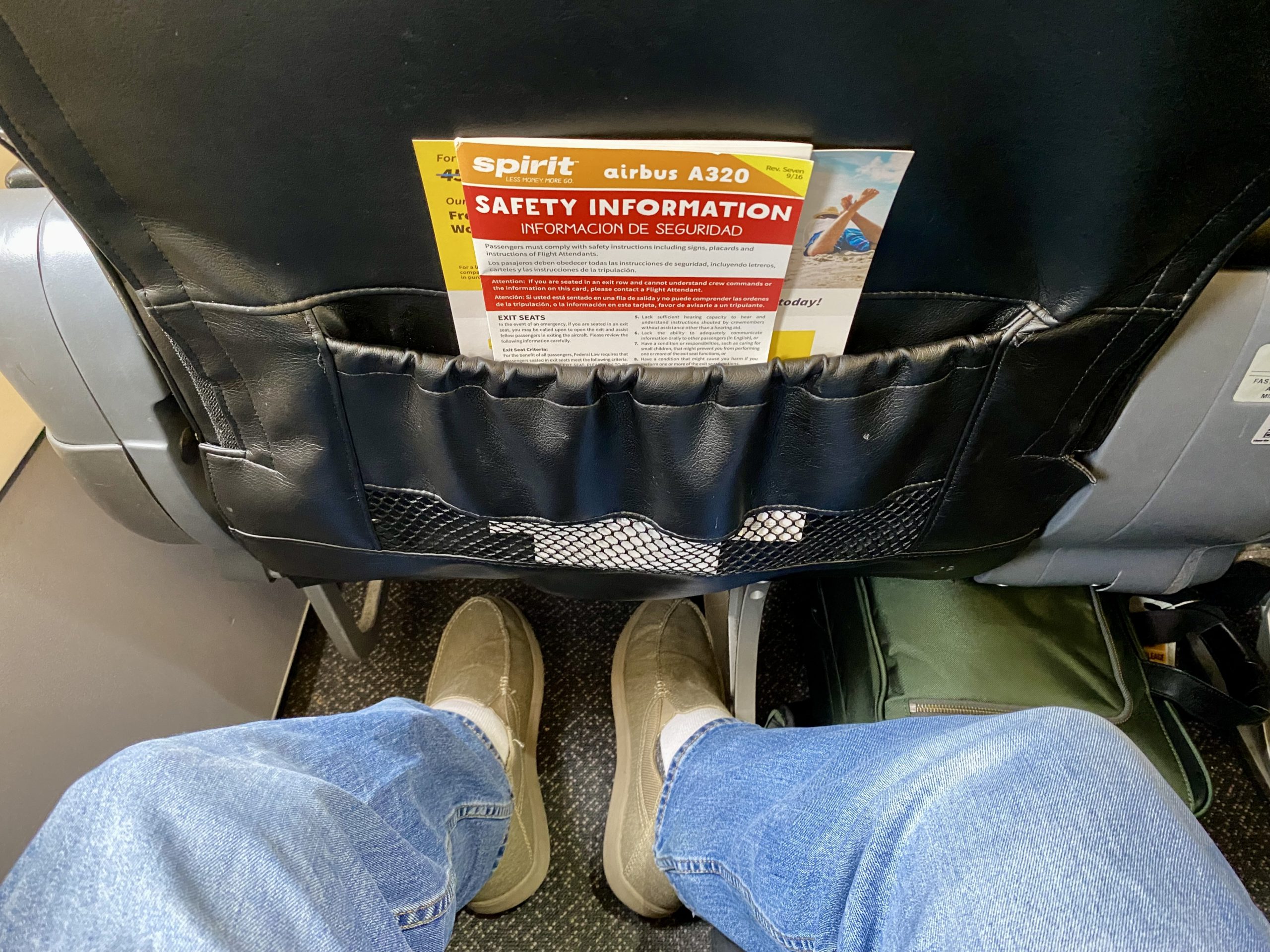 a person's legs and feet in a seat with a safety information in the pocket