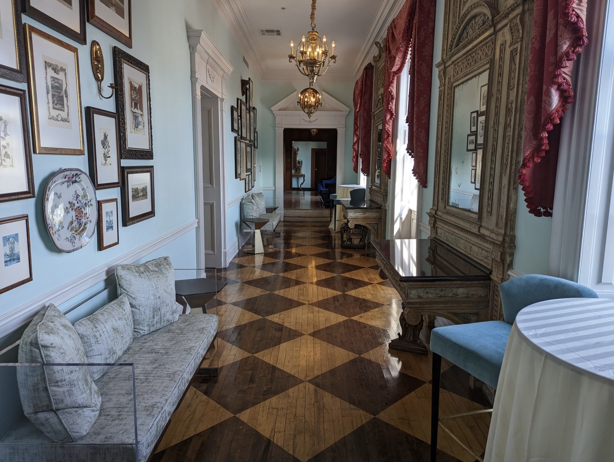 a long hallway with a checkered floor and a chandelier