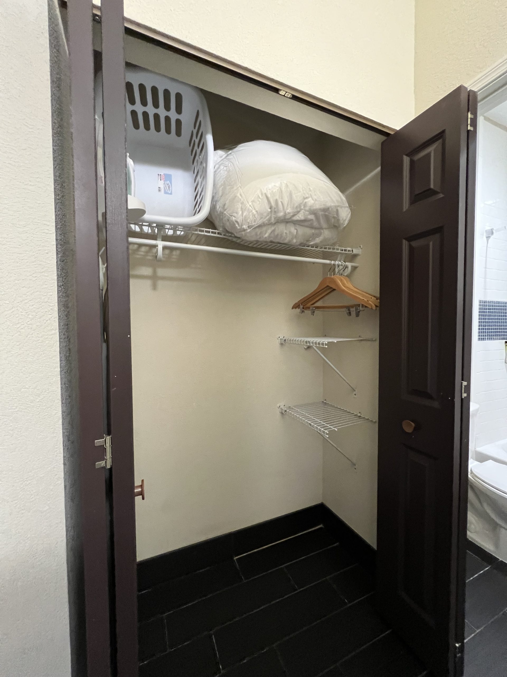 a closet with a laundry basket and clothes rack