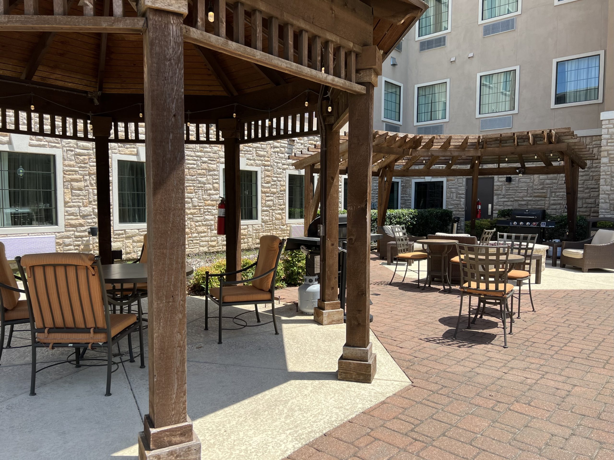 a patio with a wooden structure and chairs