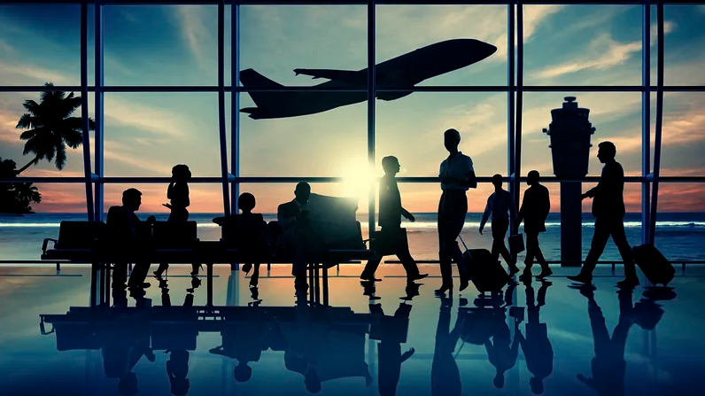 silhouettes of people walking in an airport terminal with a plane in the background