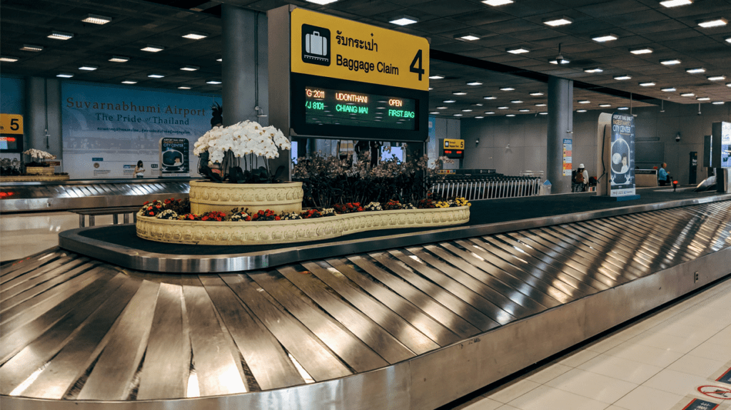 a baggage claim area with a sign and flowers