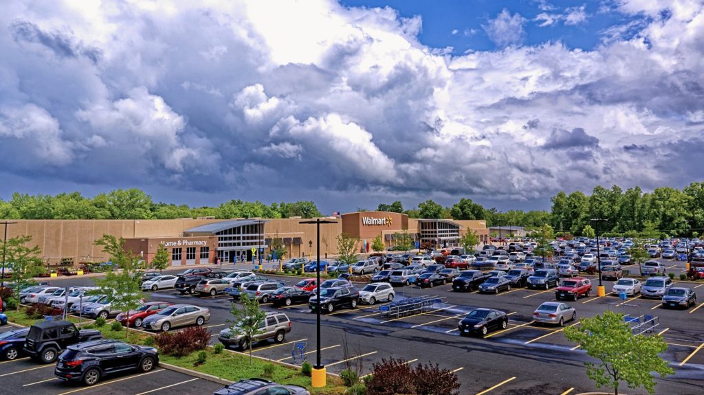 a parking lot with cars and a building with clouds in the sky