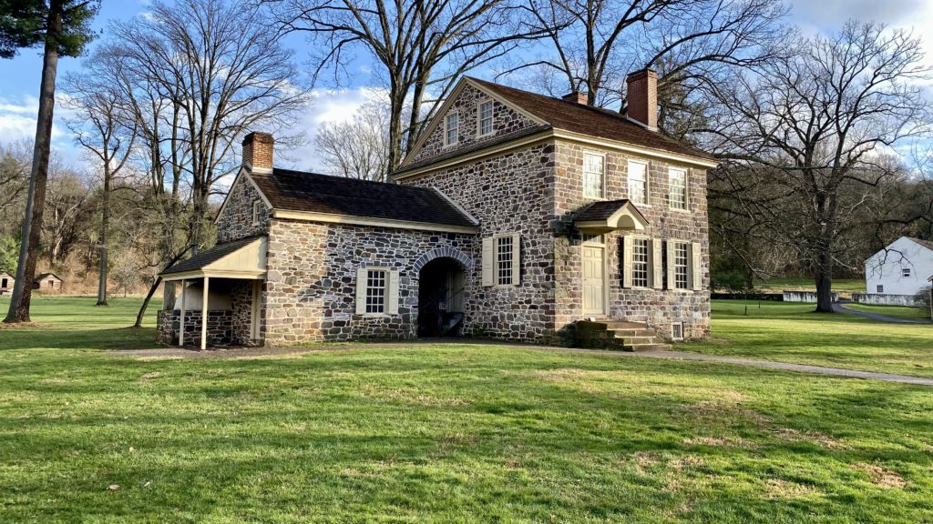 a stone house with a lawn and trees in the background with Washington's Headquarters in the background