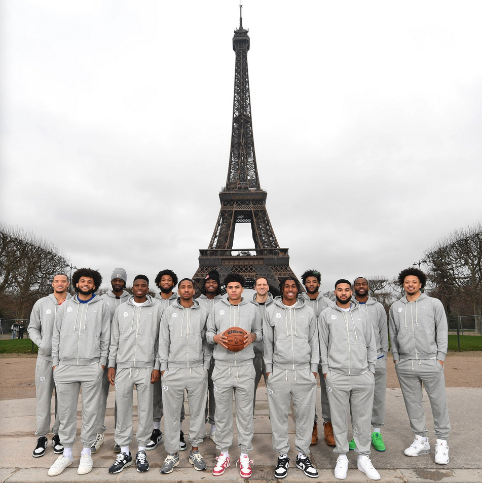 a group of men in grey tracksuits posing for a photo in front of a tower