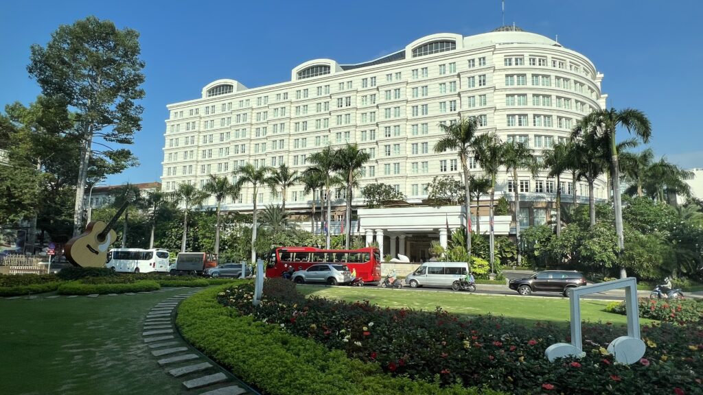 a large white building with palm trees and a road