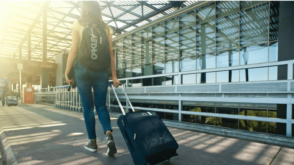 a woman with a backpack pulling a suitcase