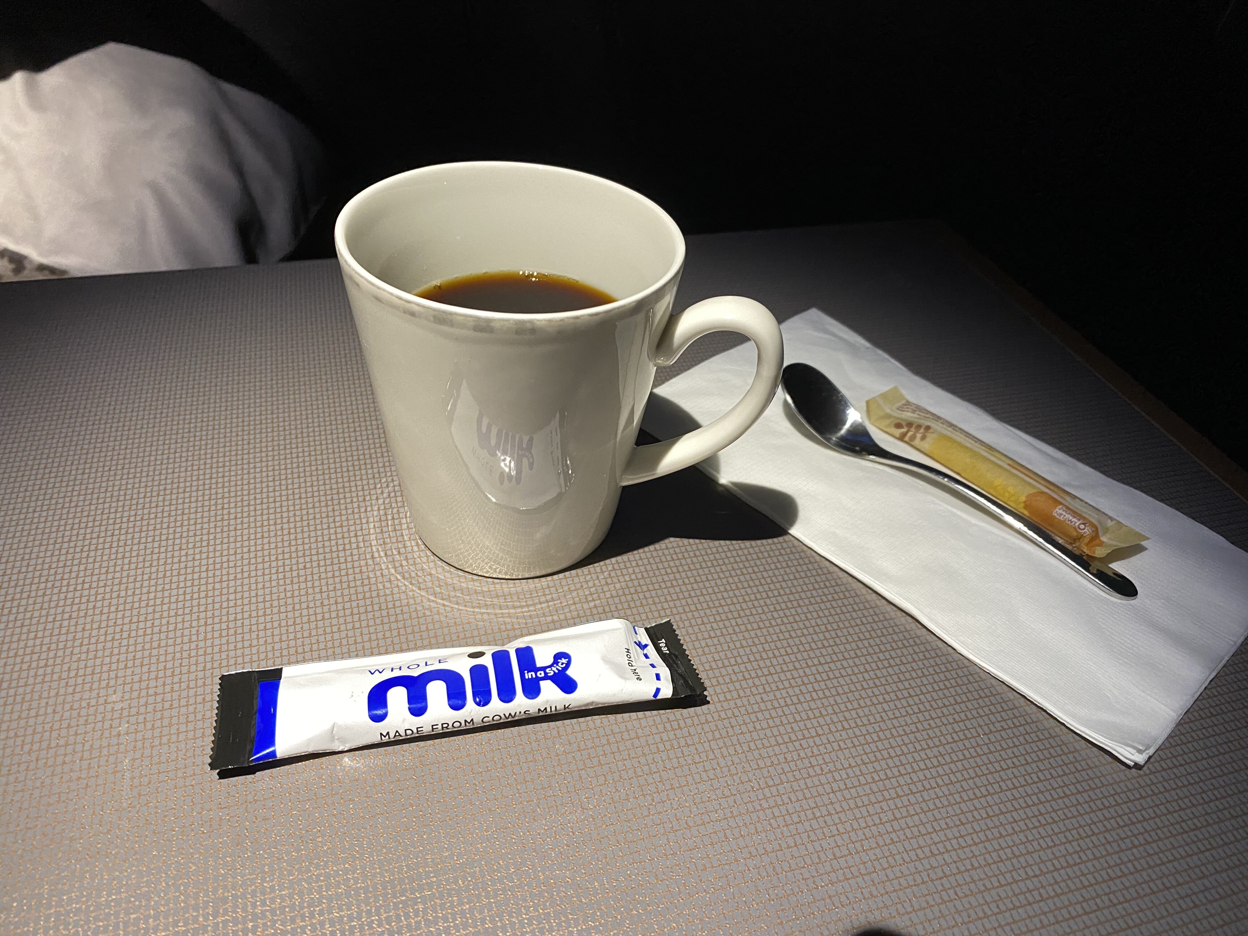 a cup of coffee and a packet of milk on a table