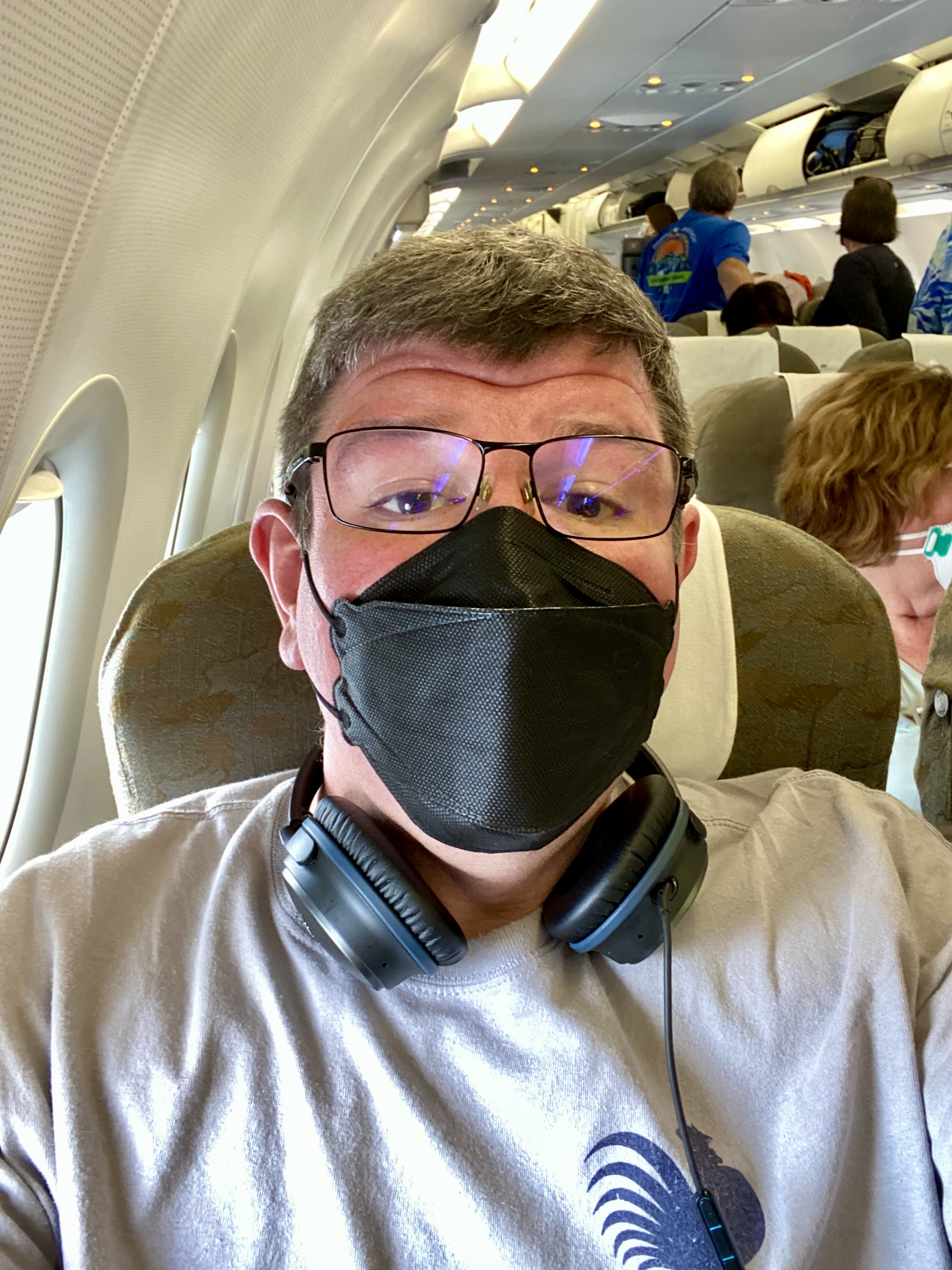 a man wearing a mask and glasses sitting in an airplane