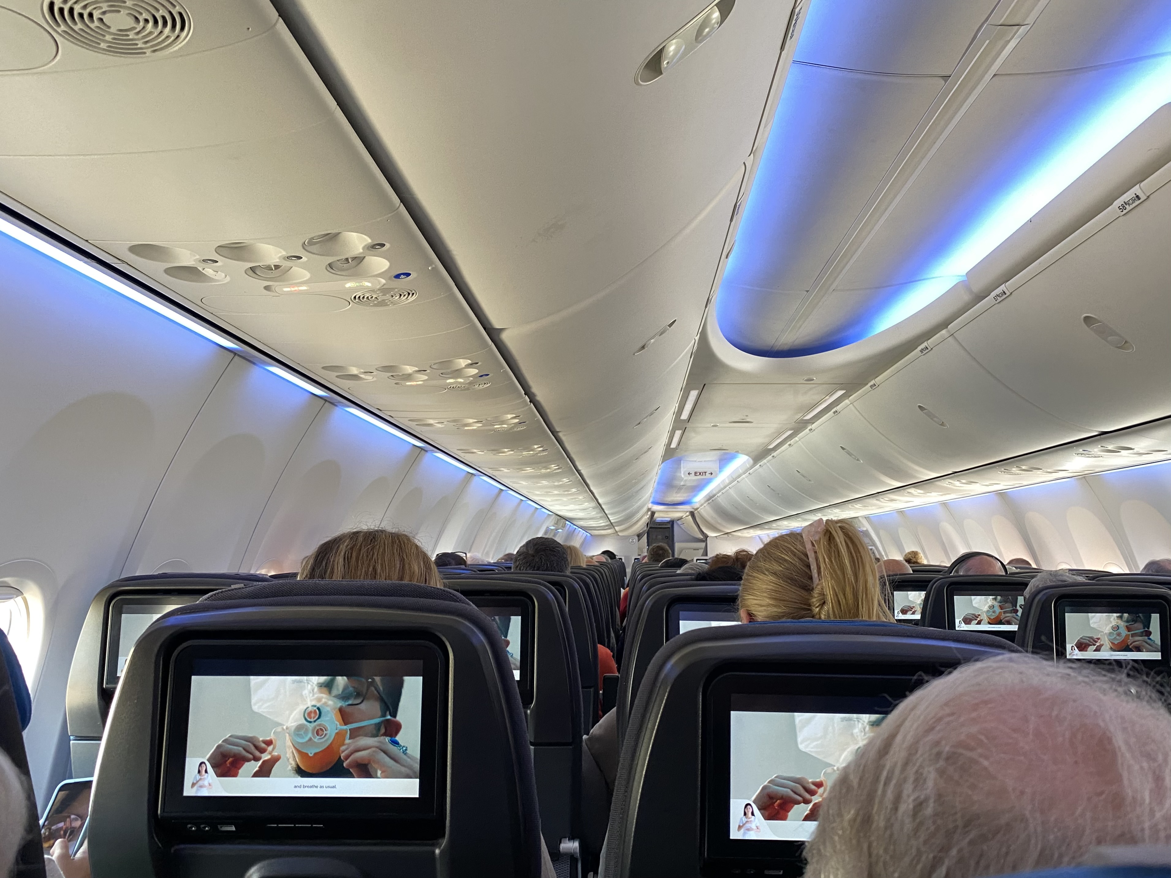 a row of seats with a television screen on the back of a plane
