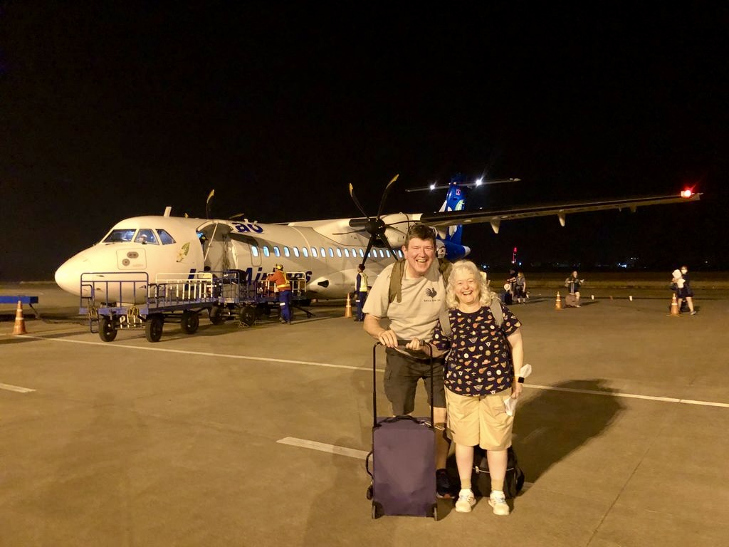 a man and woman standing in front of an airplane