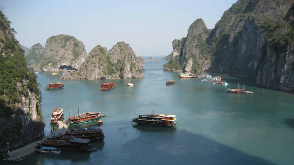 boats in a body of water with mountains in the background with Ha Long Bay in the background