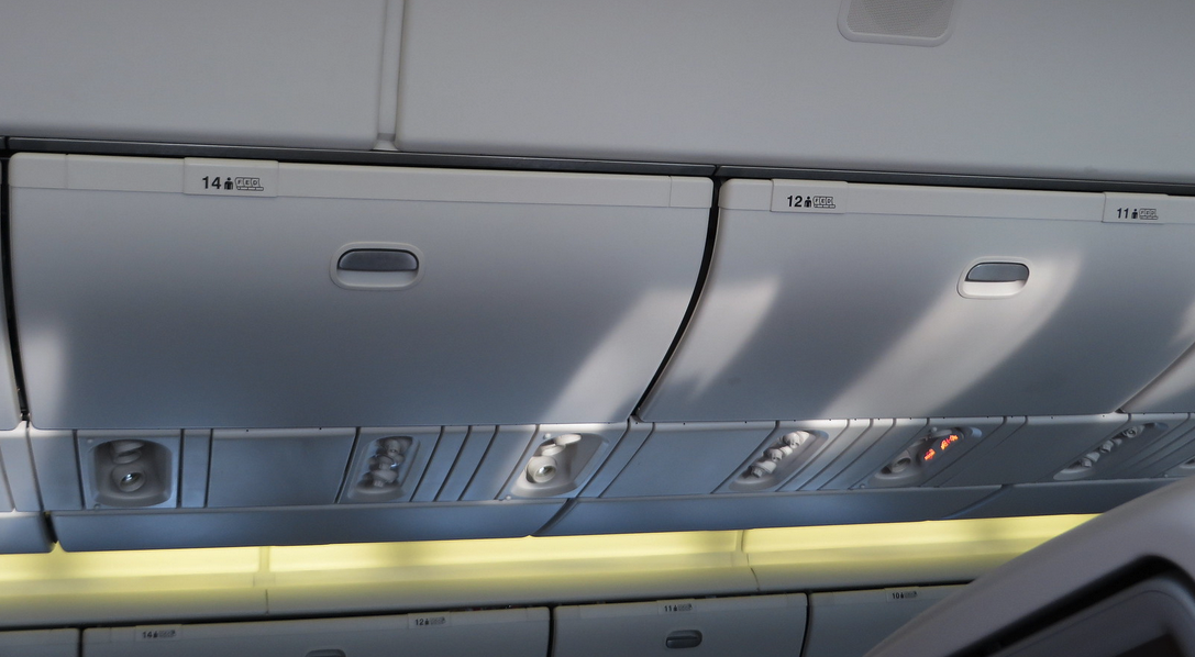 an overhead compartment with lights and a shelf