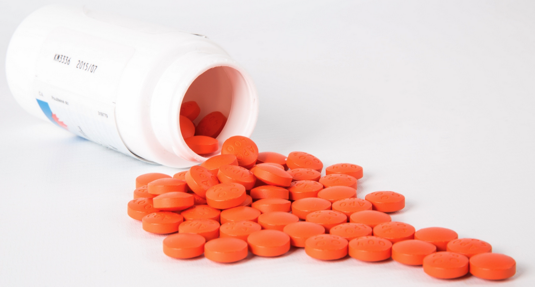 a white bottle with orange pills spilling out