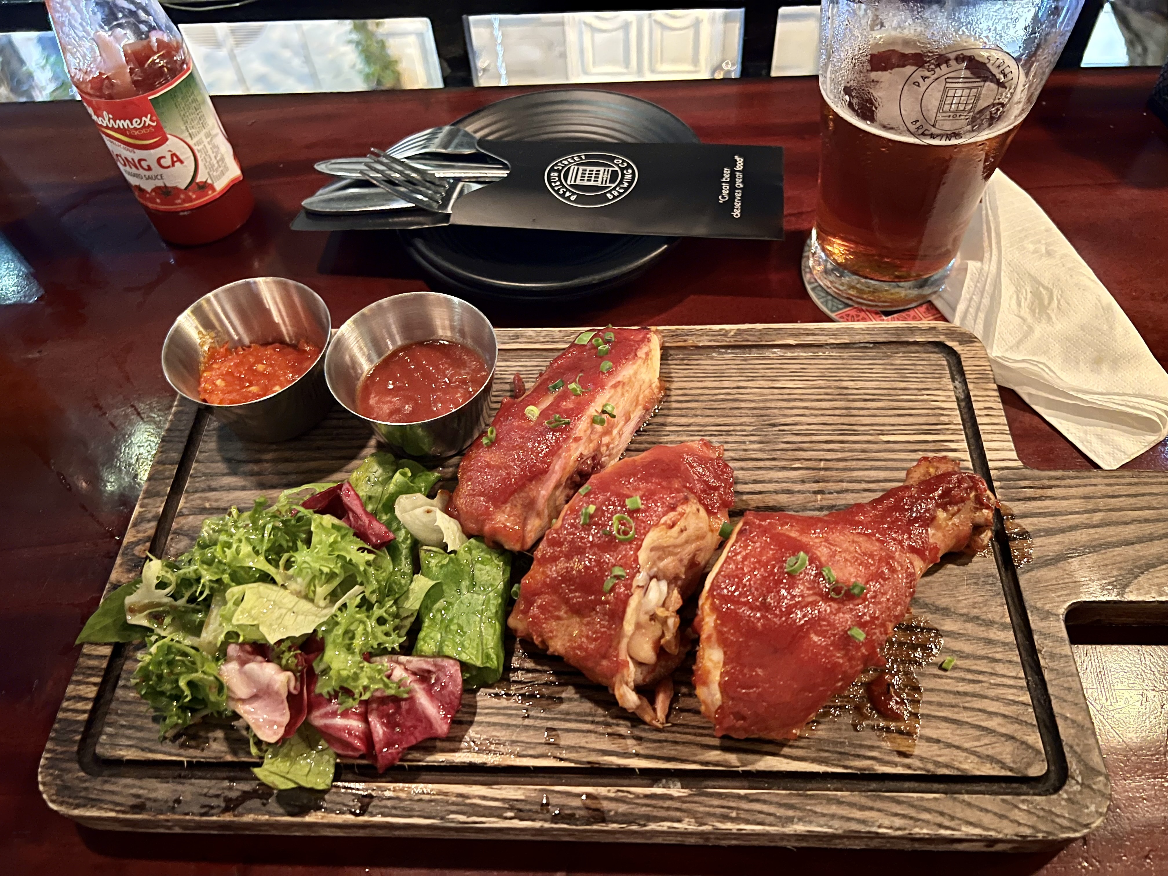 a wooden board with meat and salad on it