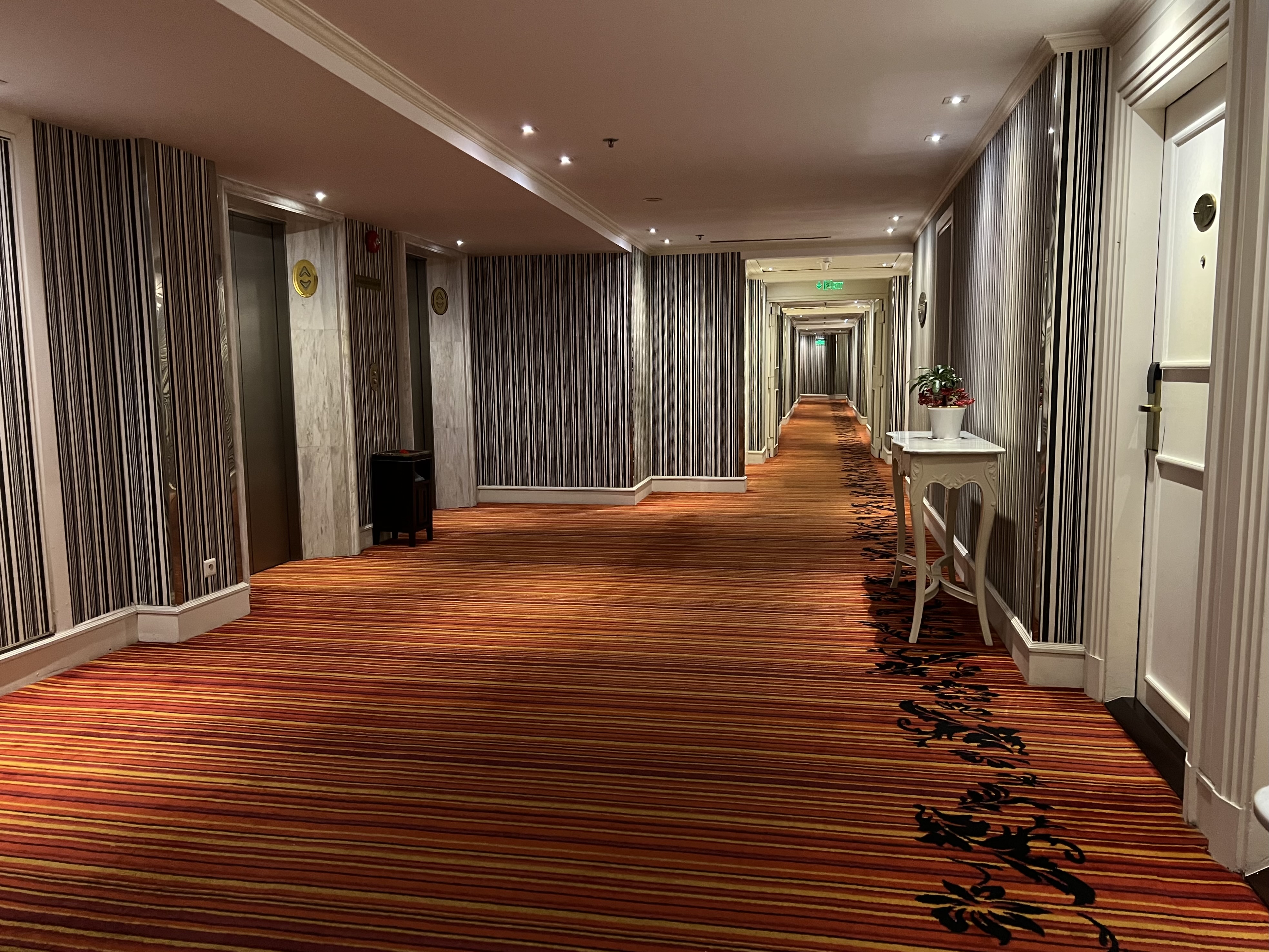 a hallway with striped carpet and a table