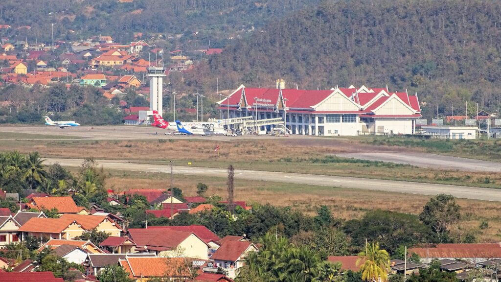 a building with red roof and a runway and buildings in the background