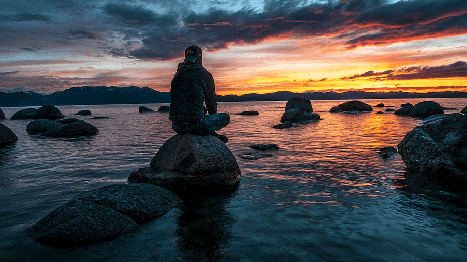 a person sitting on a rock in the water