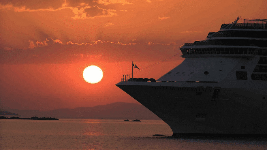 a cruise ship in the water at sunset