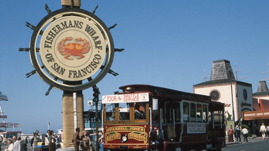 a sign on a trolley with Fisherman's Wharf in the background