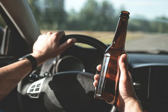 a person holding a bottle of beer while driving