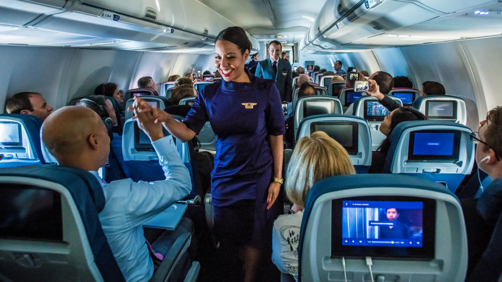 a woman in a blue dress waving in an airplane