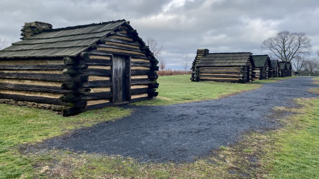 a two log cabins on a grassy field