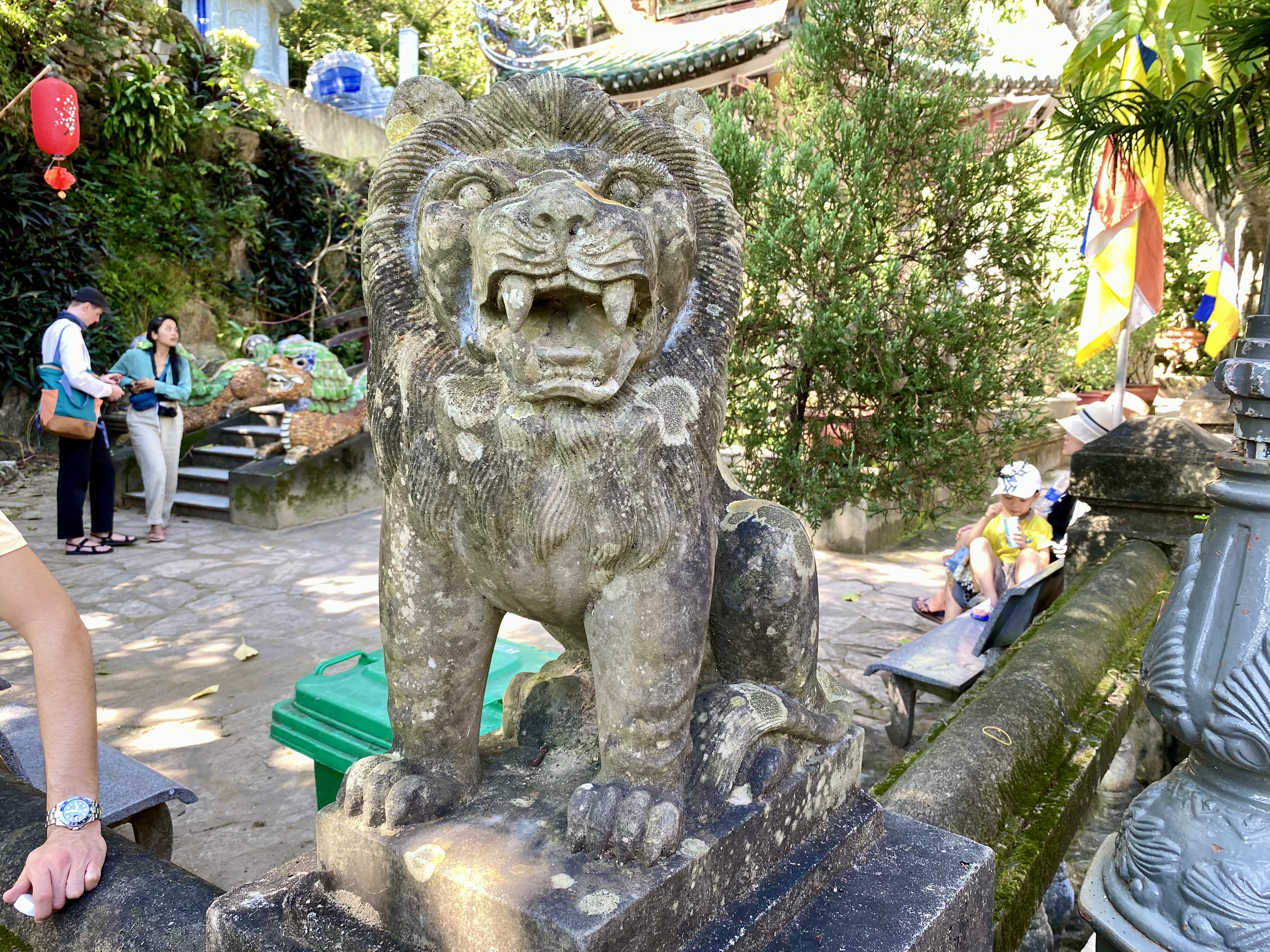 a stone lion statue with people in the background