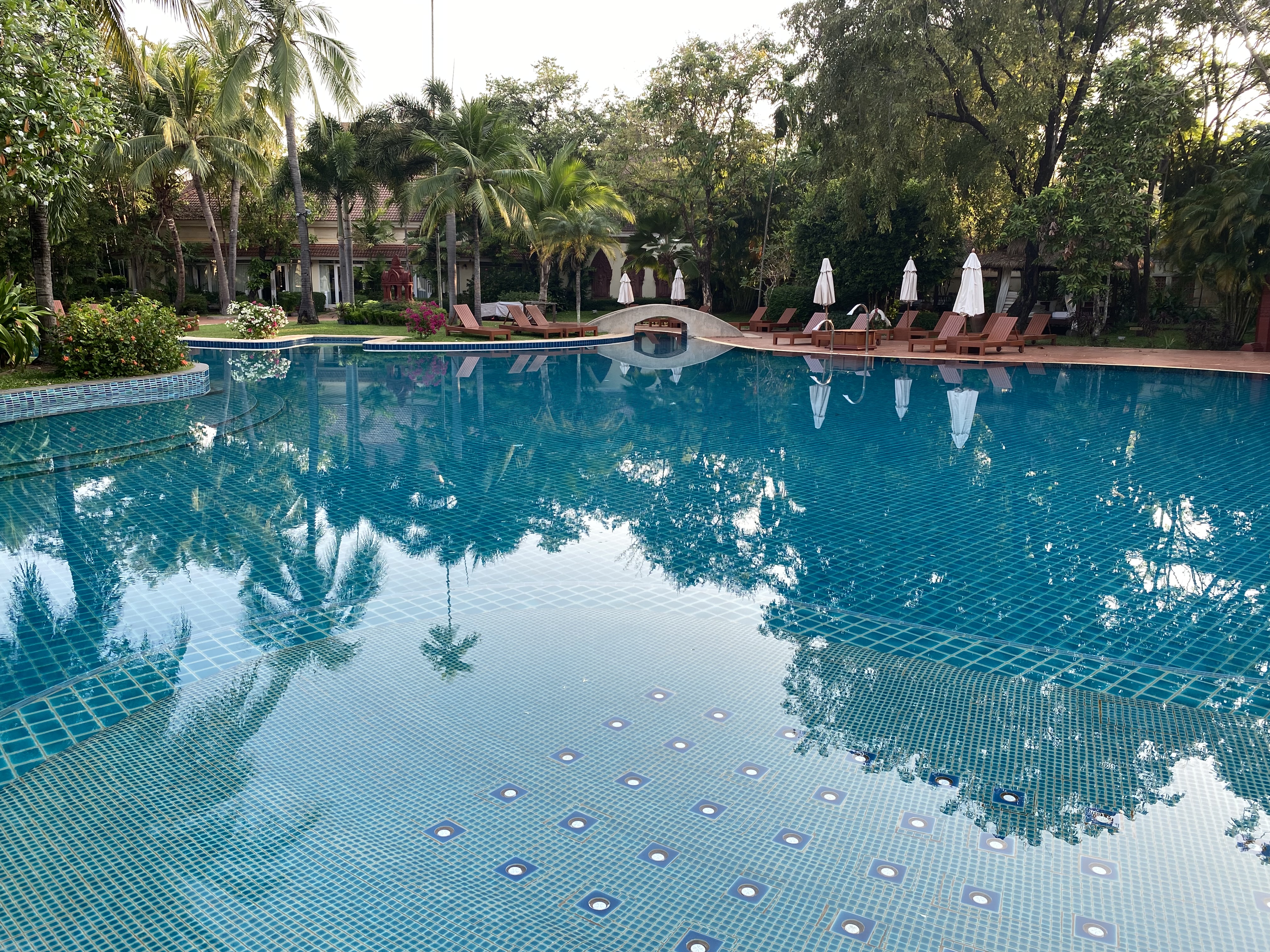 a pool with lounge chairs and trees