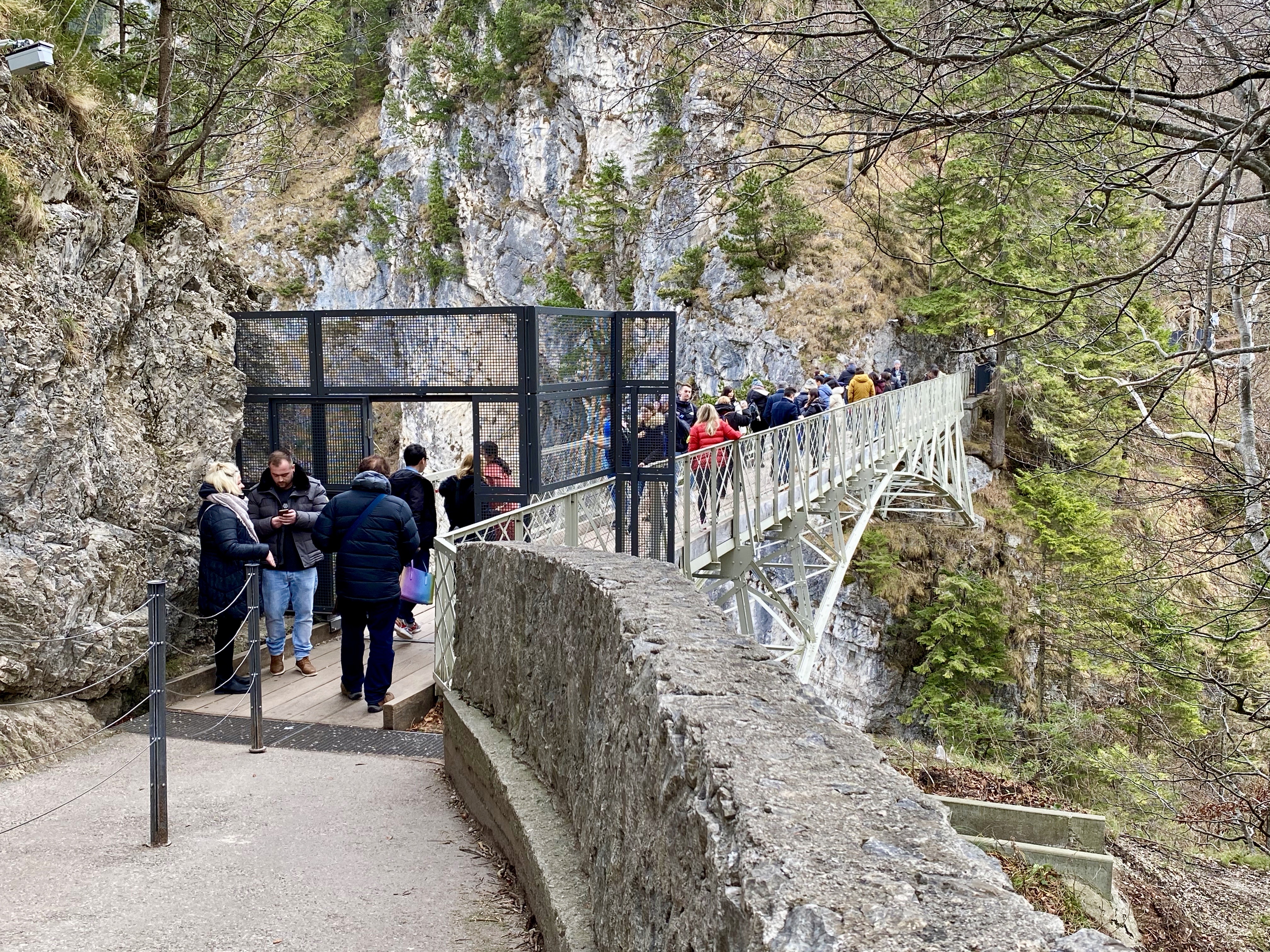 a group of people walking on a bridge over a cliff