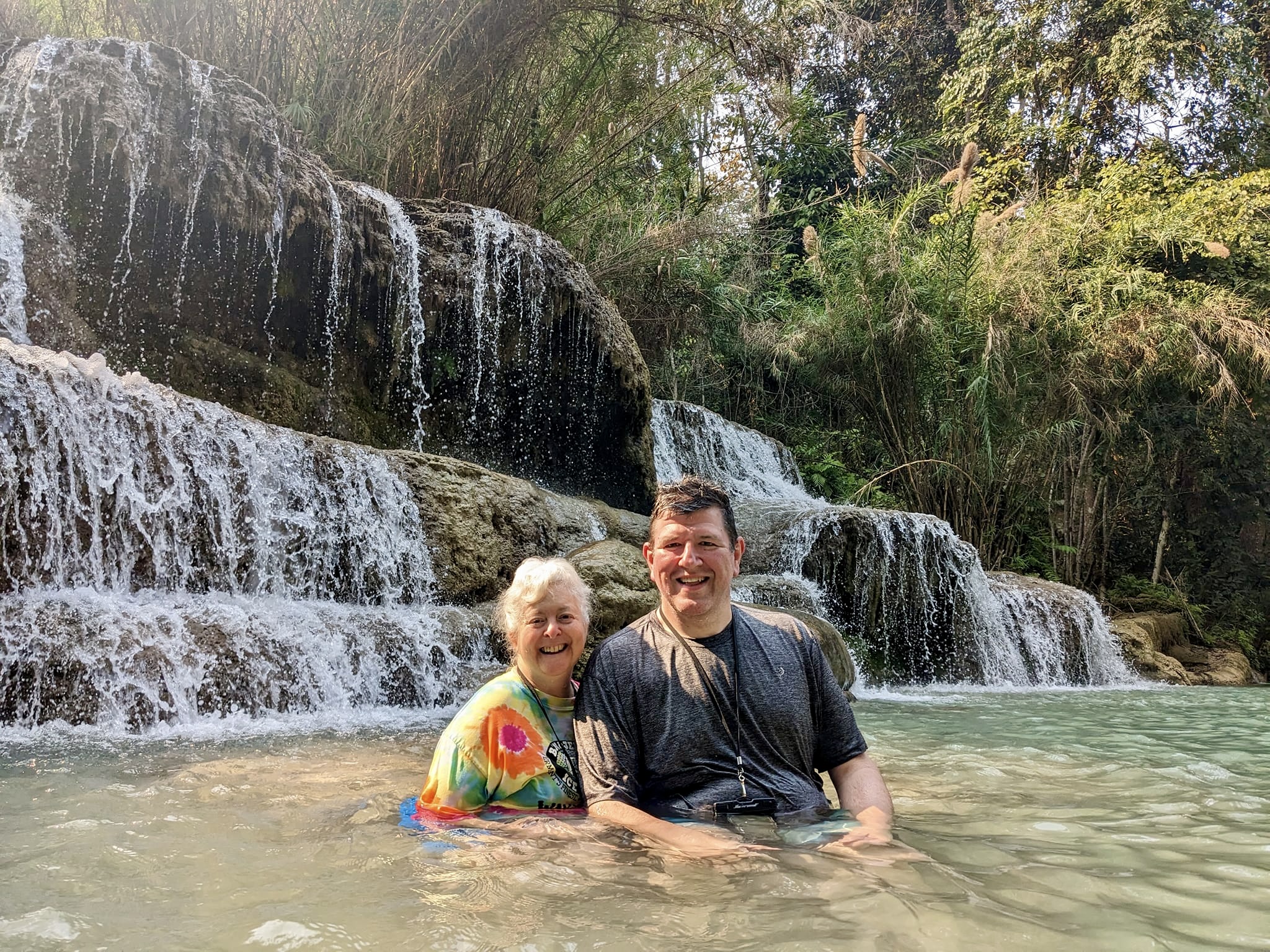 a man and woman in water with a waterfall